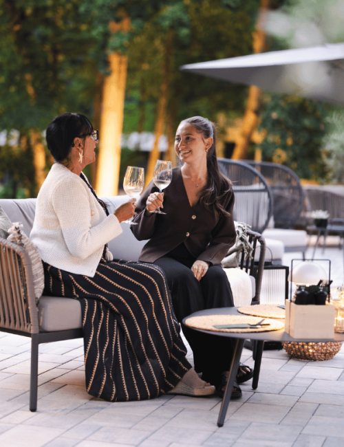 Zwei Frauen sitzen auf der Terrasse und trinken Wein